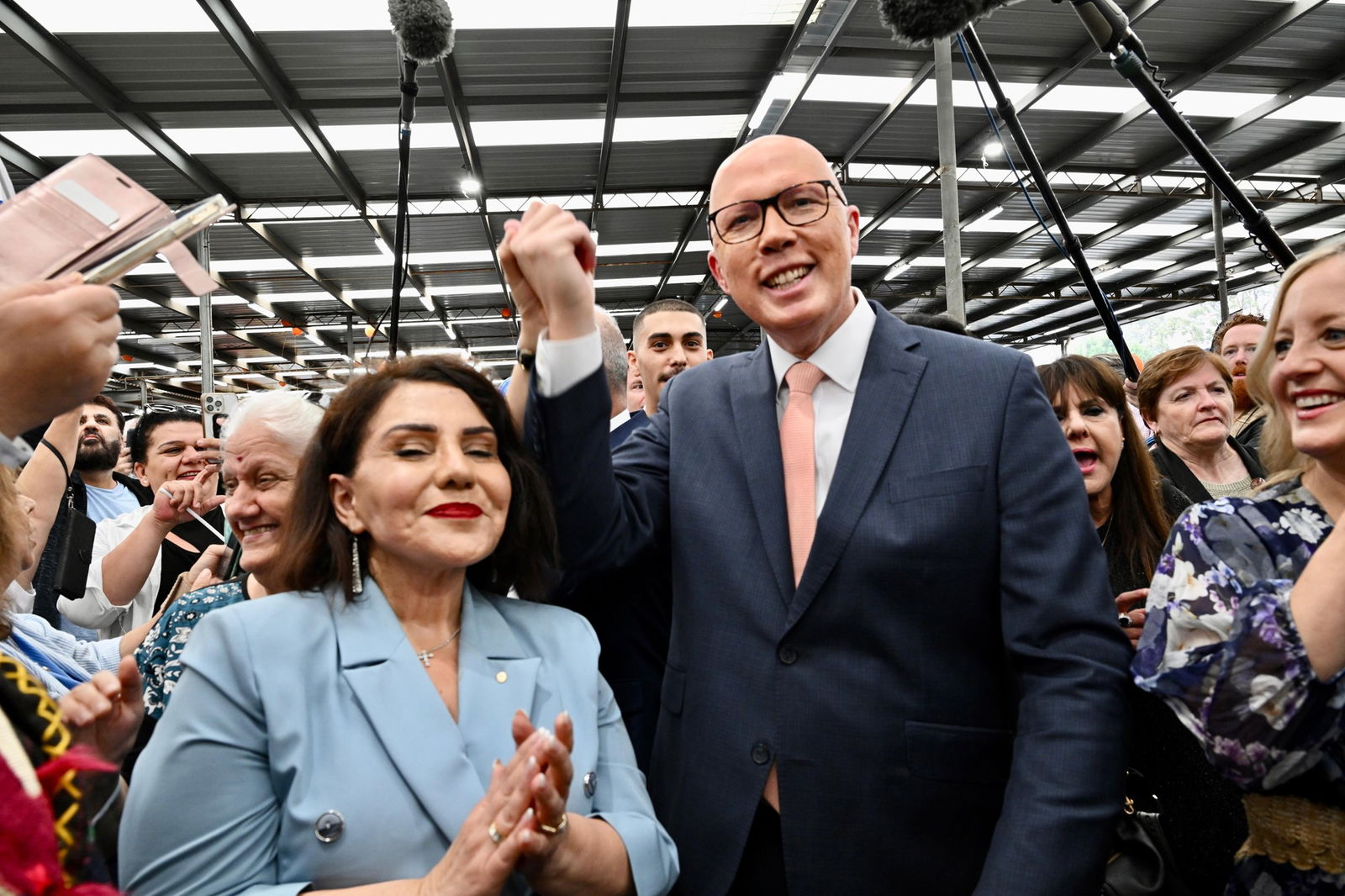 Dutton raises a hand clasped with someone in the crowd