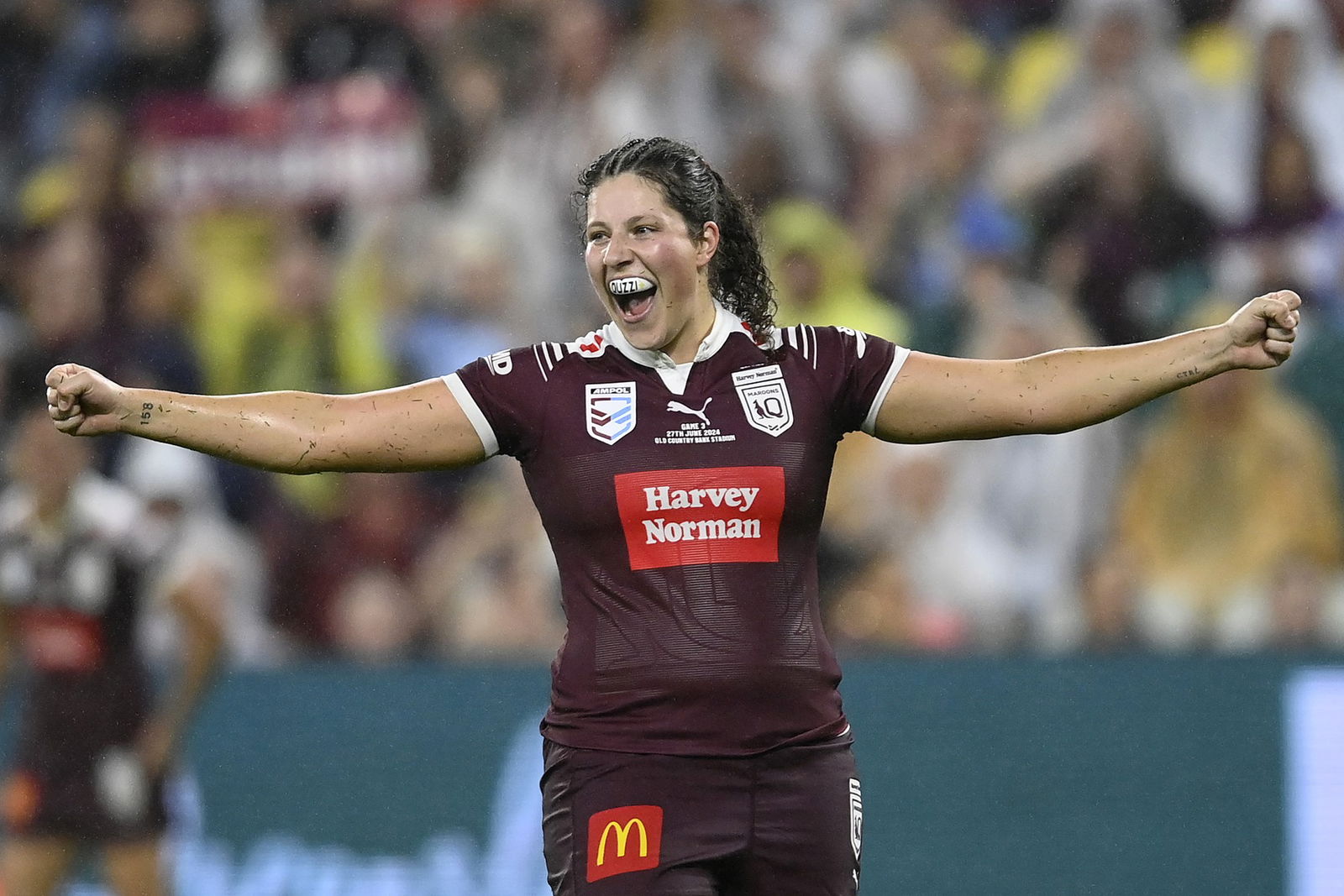 Maroons player Chelsea Lenarduzzi smiles and stretches her arms out.