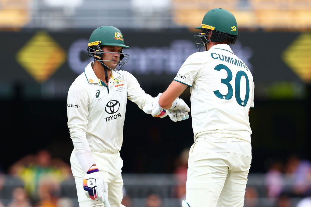 Australia batters Alex Carey and Pat Cummins bump fists during a Test.