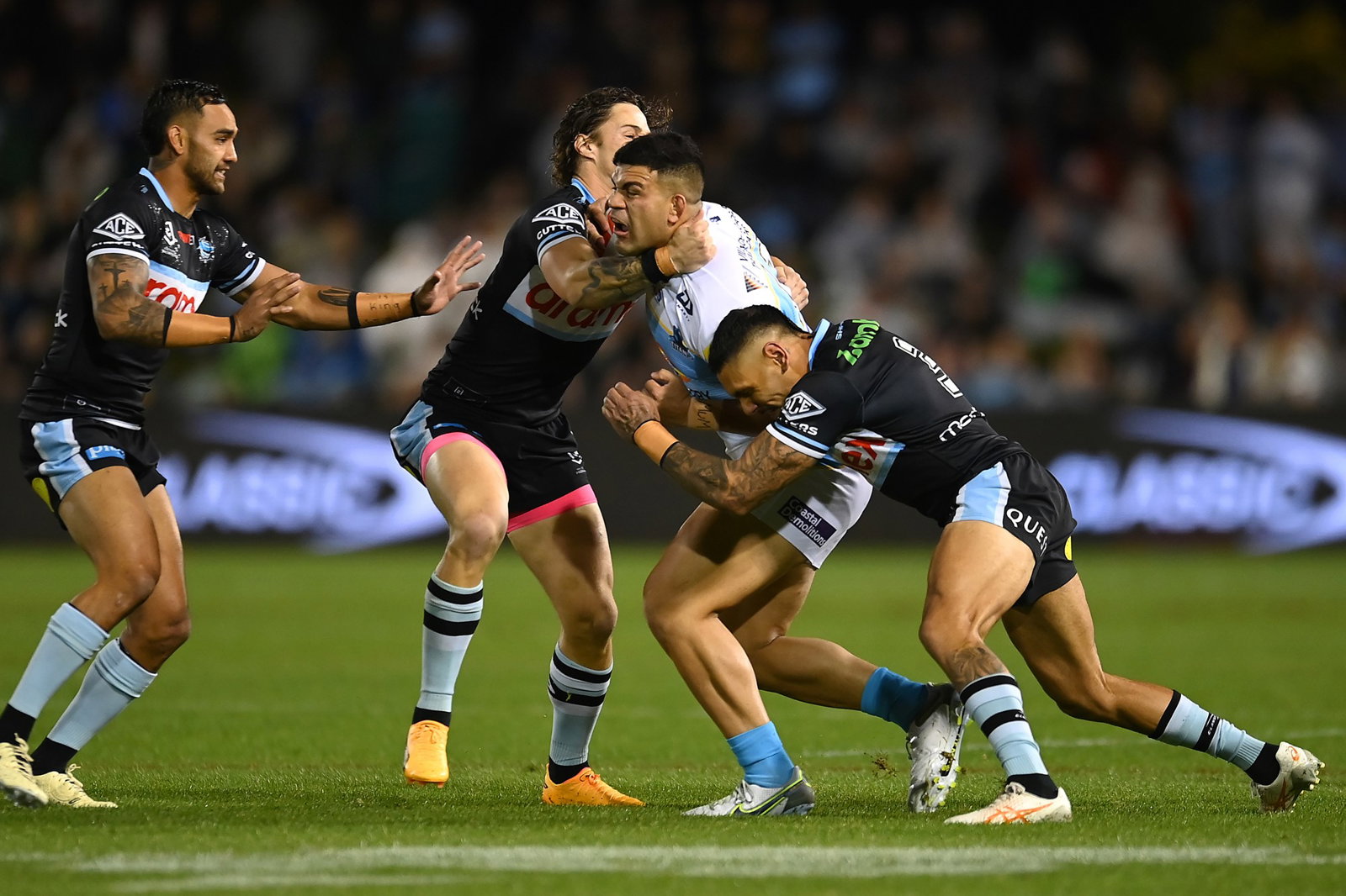 David Fifita is tackled by three Sharks players.