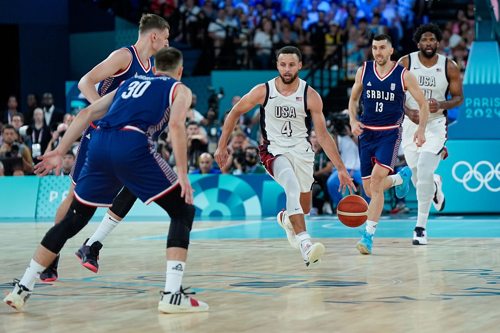 A basketballer in white runs with the ball.