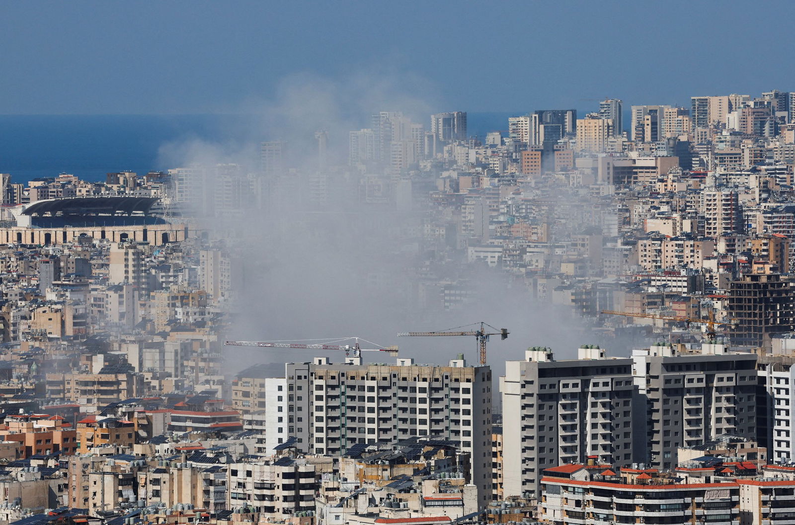 Smoke billowing from between buildings in a wide city scape