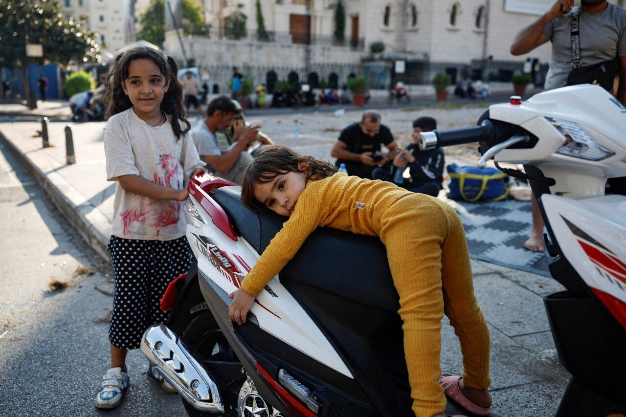 Two young girls play near a motorbike.