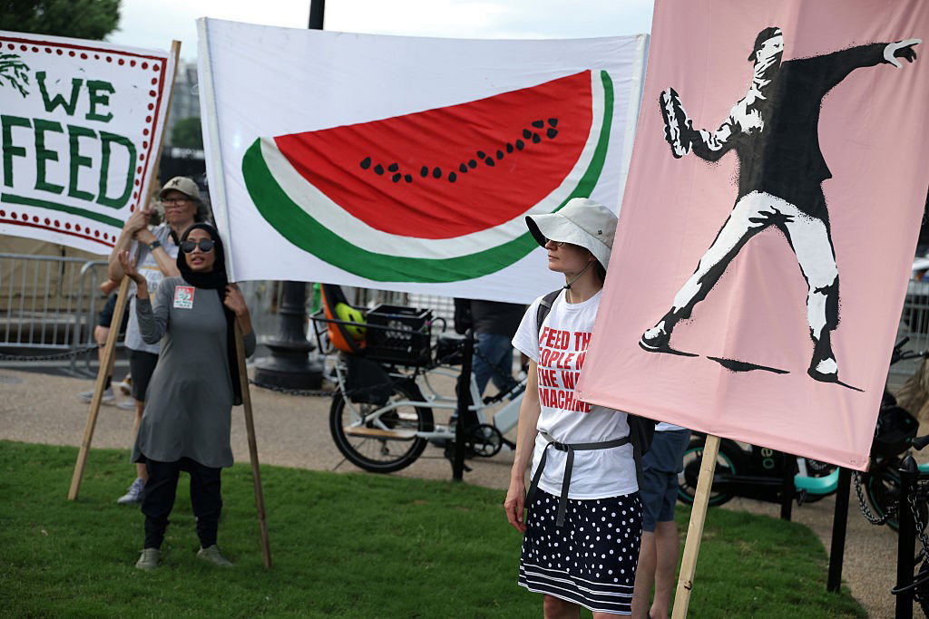 Protesters holding watermelon signs and a Banksy.