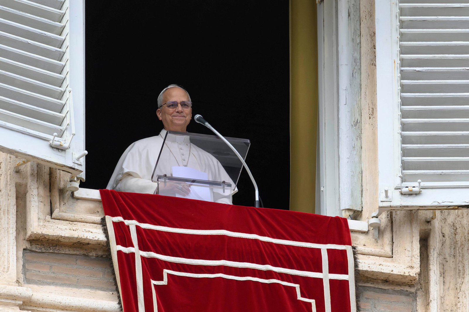 El Papa León aparece en una ventana, vestido de blanco. 