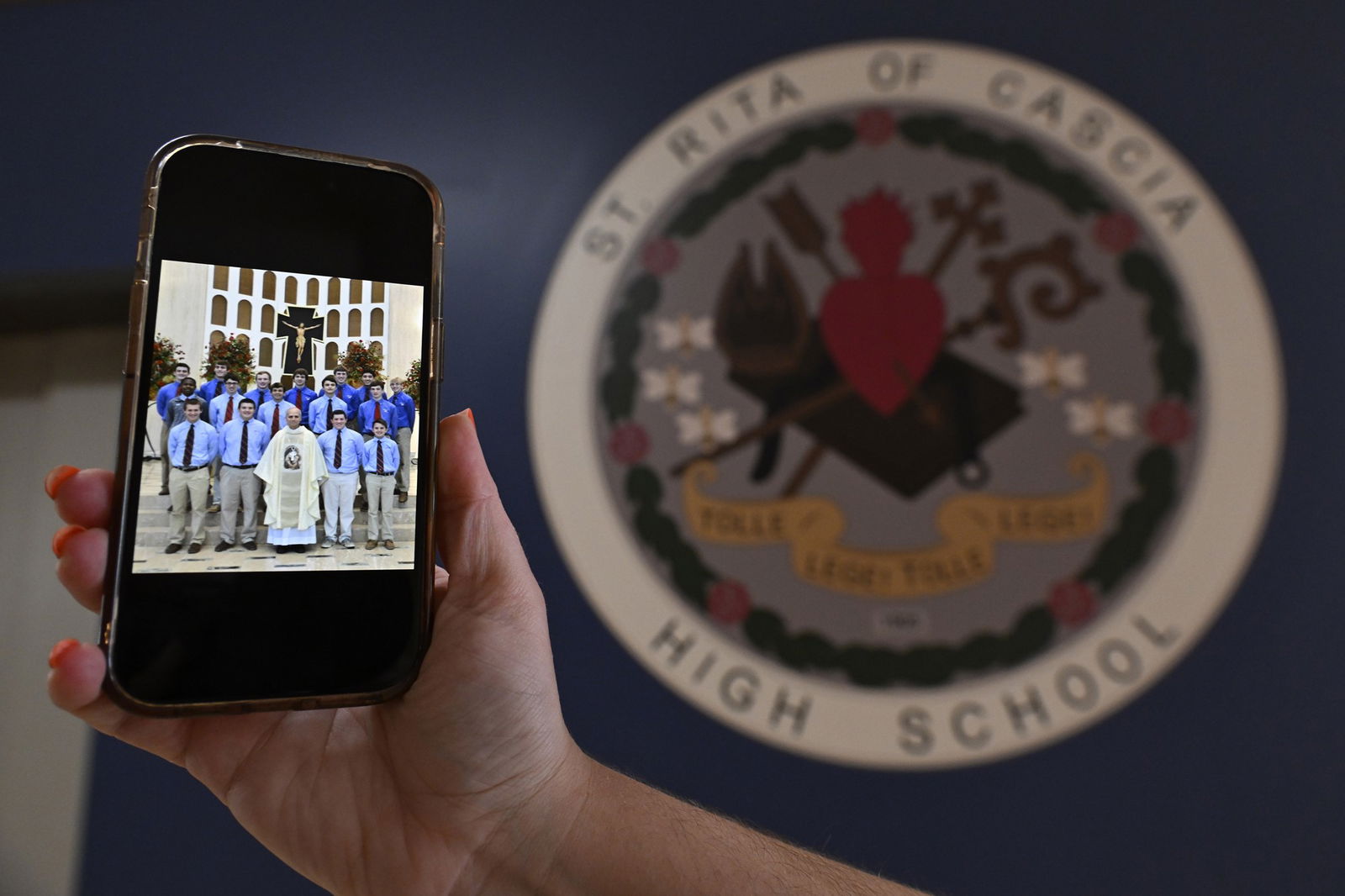 A photo of Pope Leo and students is shown on a phone