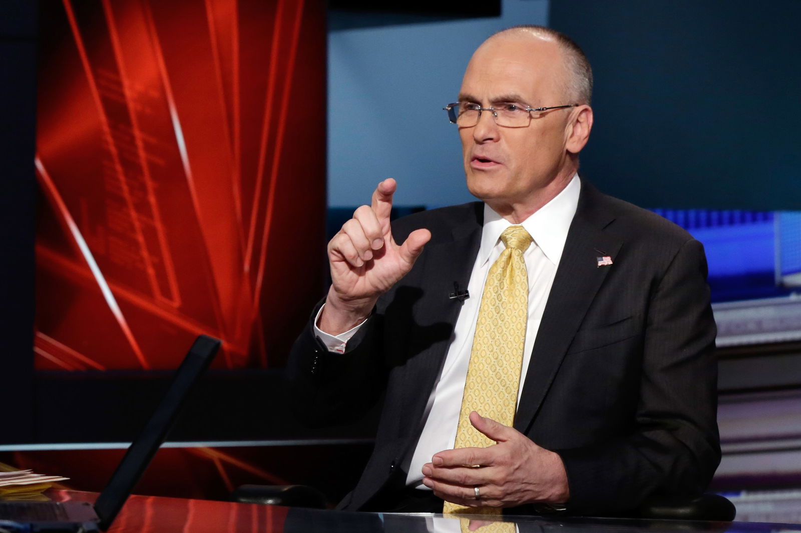 Andrew Puzder speaking at a desk with one hand lifted.
