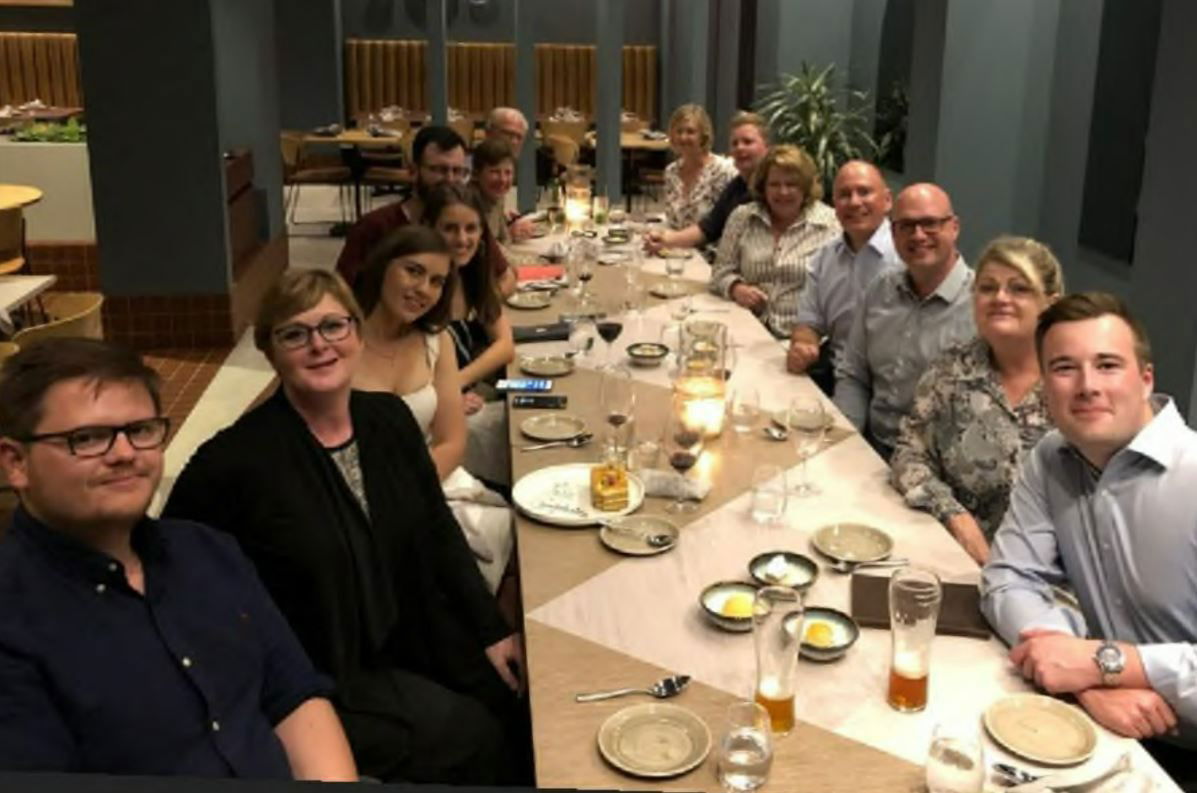 A large group of people at a long dinner party table.