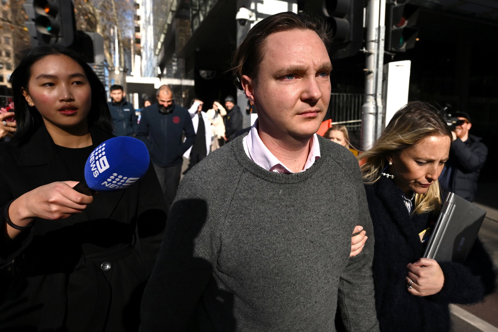 A man leaving court surrounded by media