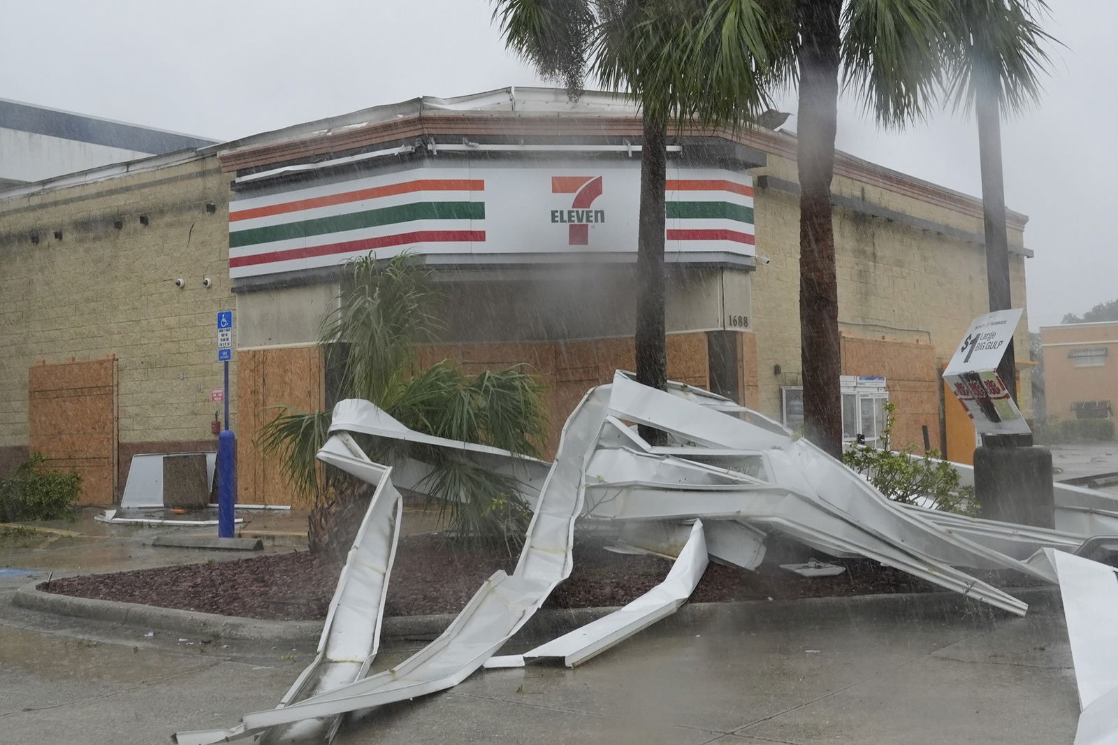 A crushed sign in front of a 7-eleven. 