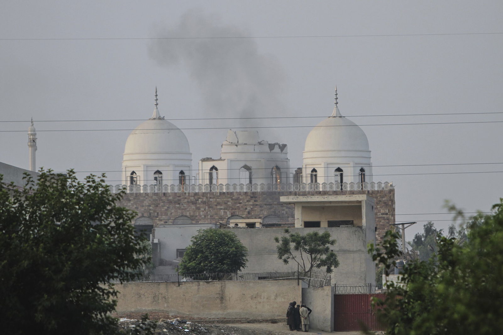 A white dome smoulders with fire and black smoke after being hit by a projectile