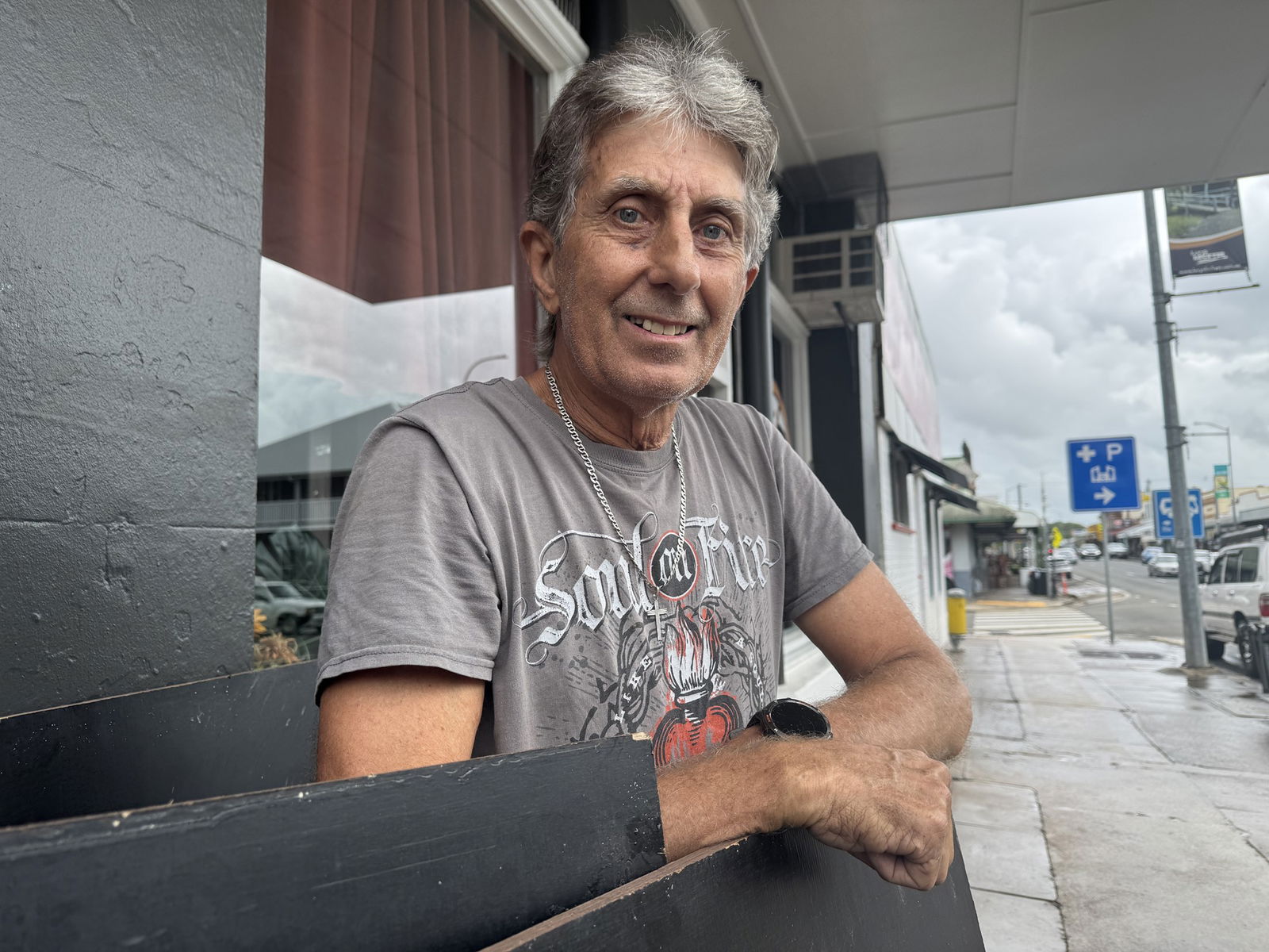 Man leaning on a bench looking at the camera. 