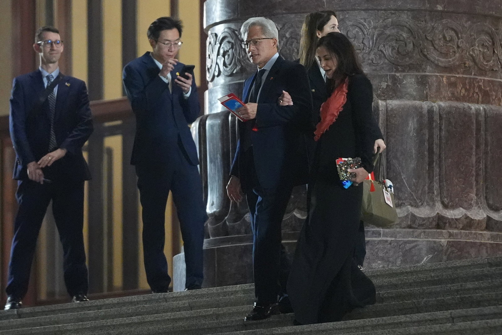 A man walks down stairs with a woman linking arms with him