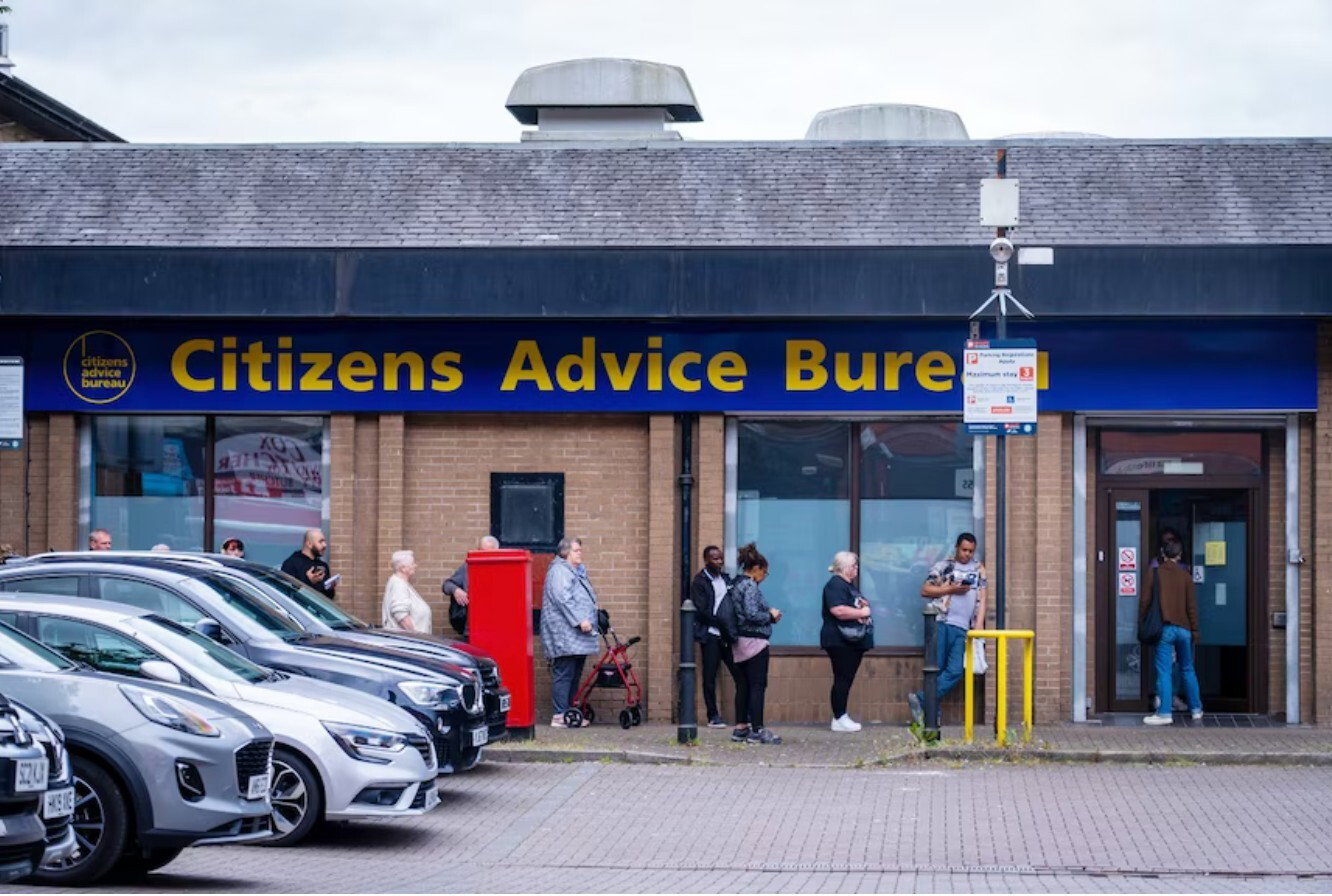 A large queue of people outside a building that says Citizens Advice Bureau on it.