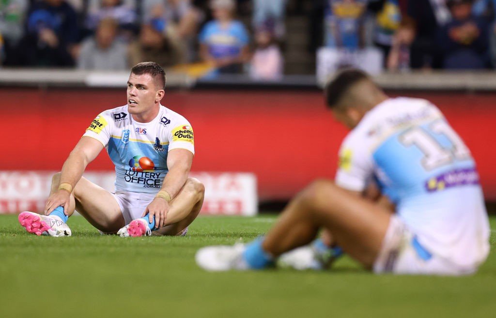 GOld Coast Titans players sit on the grass after an NRL loss.
