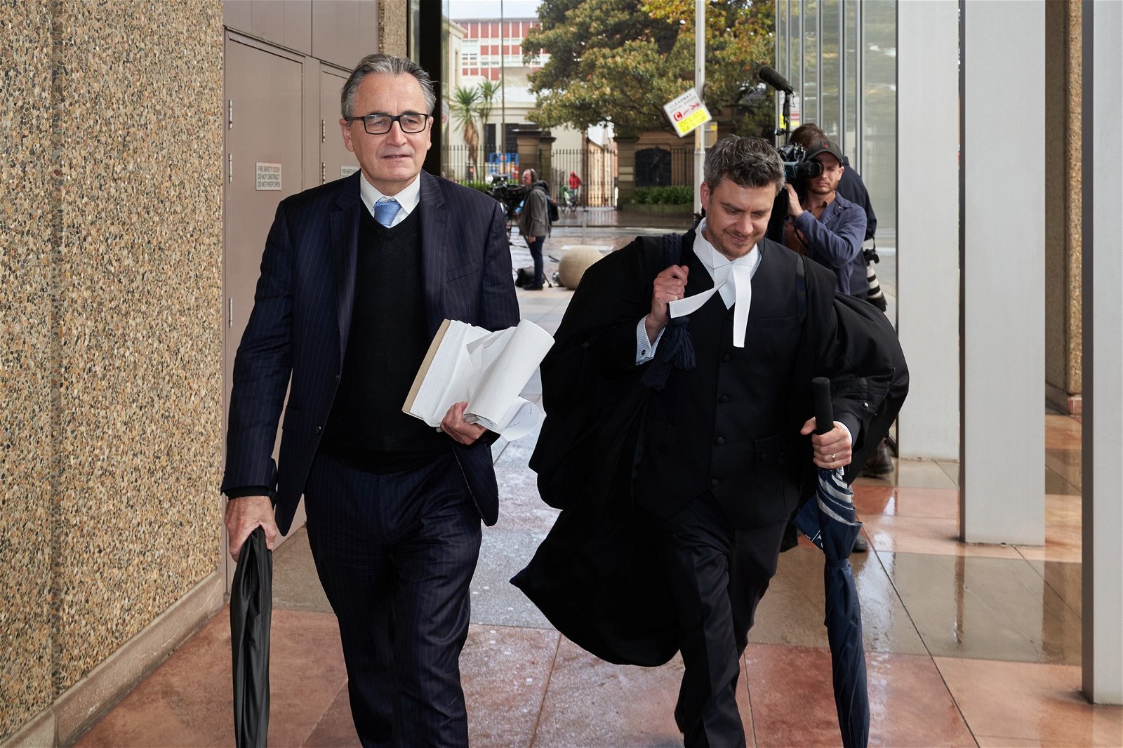 Barrister in robes walks from court with a lawyer holding a book
