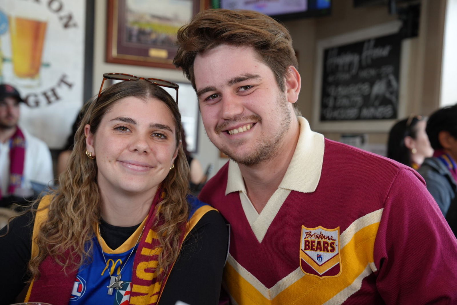 Roxanne and Jake smile, sitting in a well-lit pub.