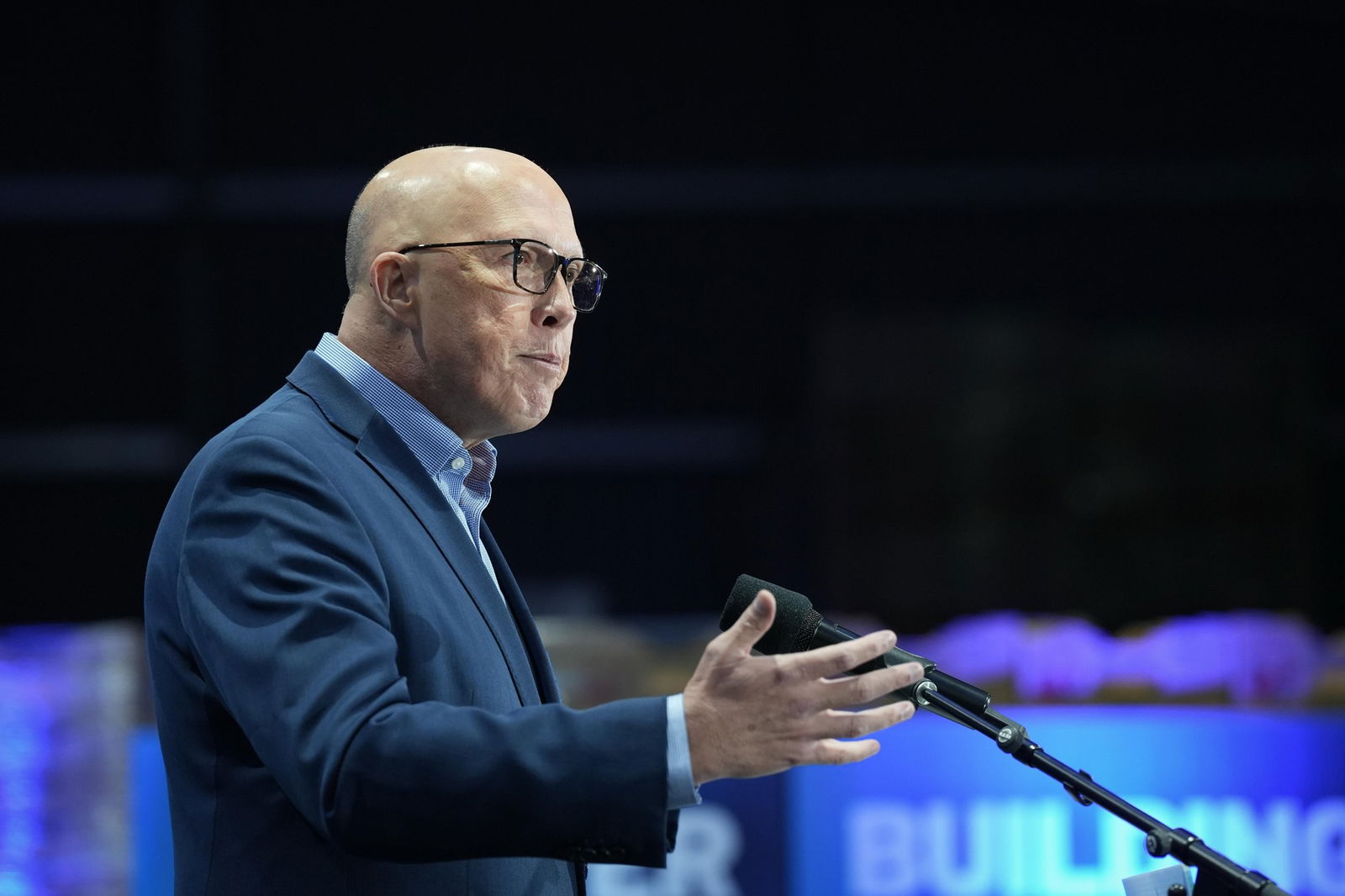 Dutton gestures with one hand as he speaks at a microphone