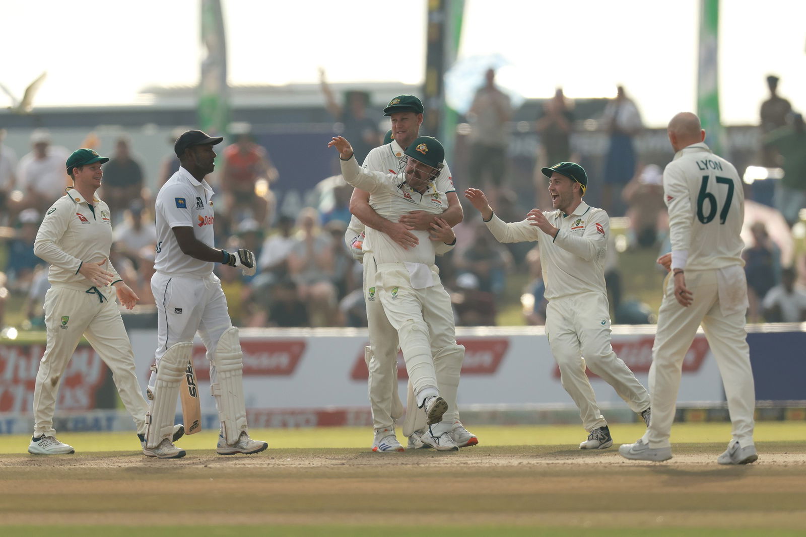 Australia celebrates with Travis Head after a catch against Sri Lanka.