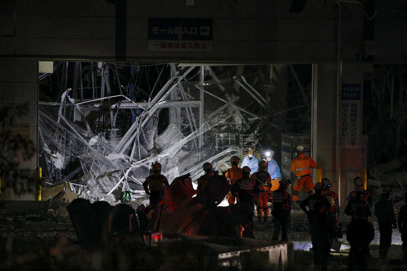 Emergency personnel stand in front of a collapsed building foundation