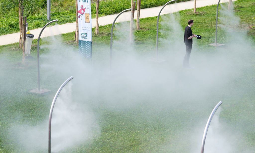 A man stands alone in a field of misters