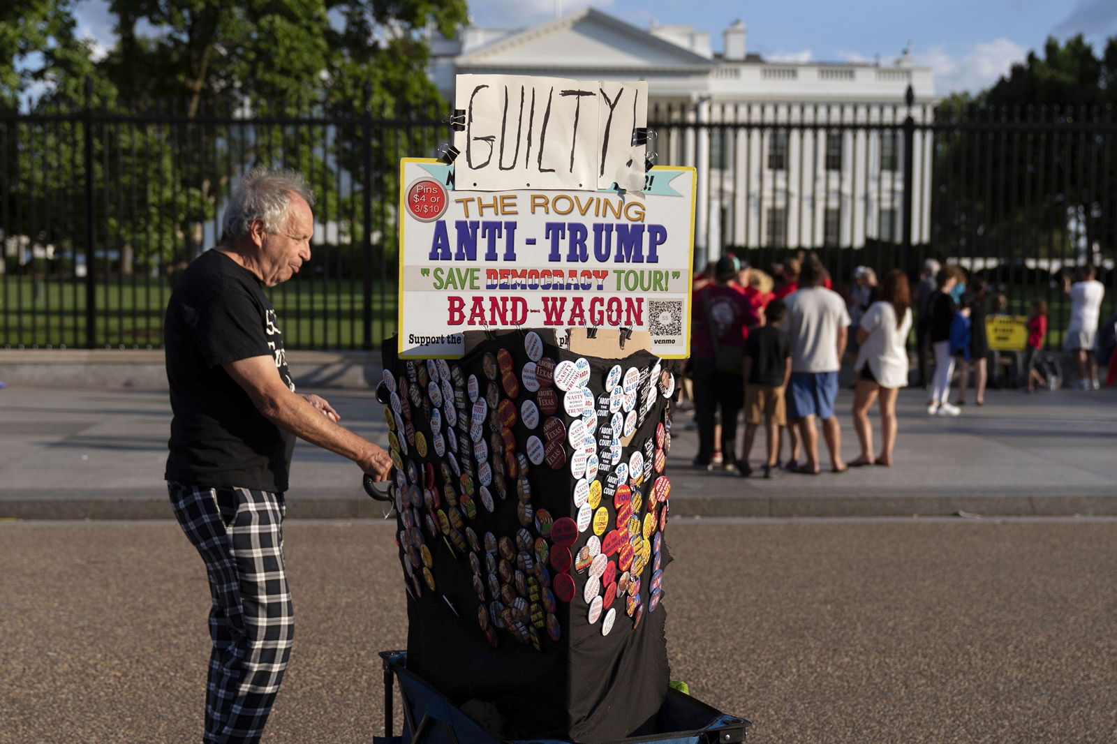 A woman with a cart covered in badges and a sign that says Guilty. 