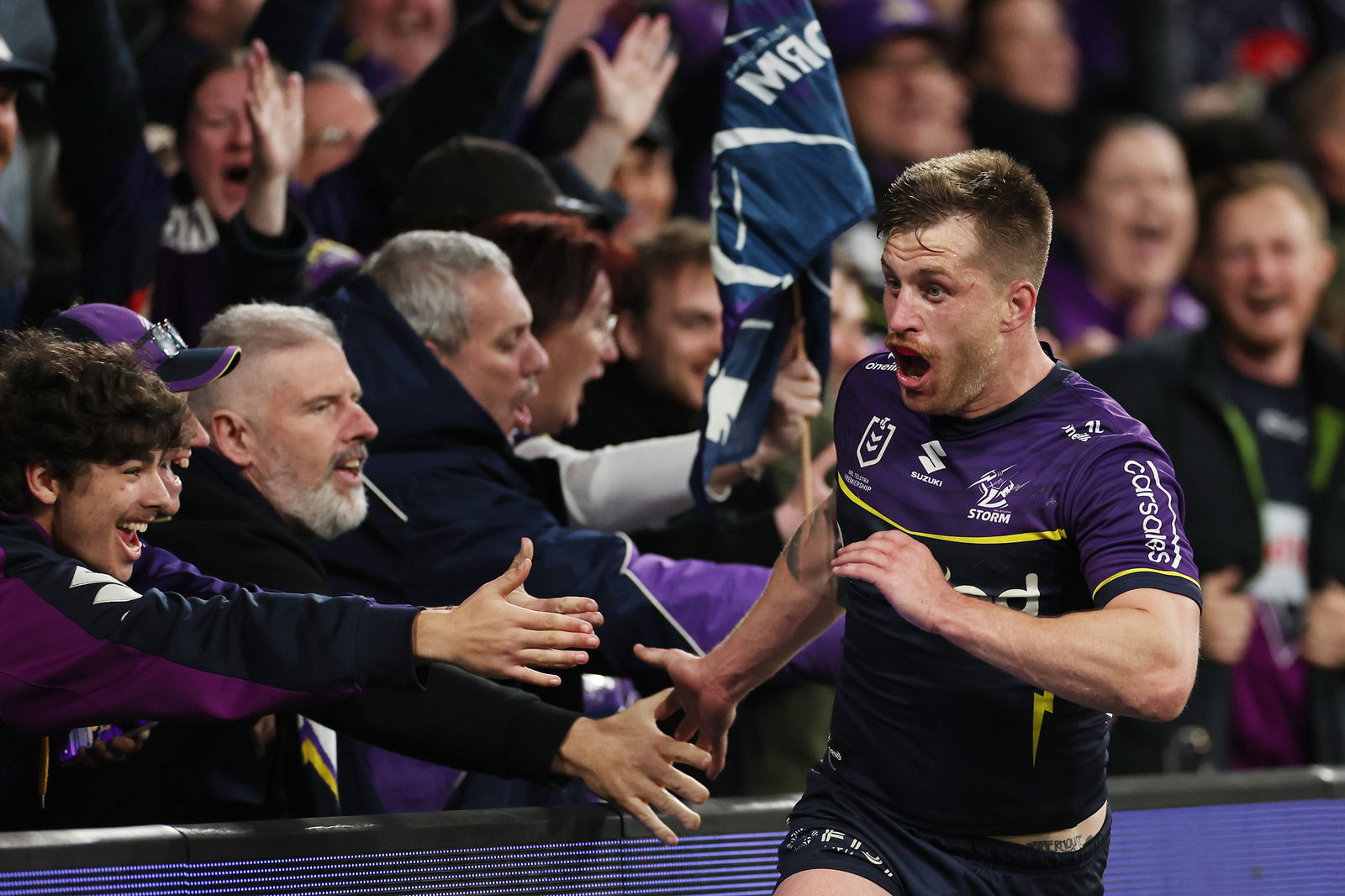 Cameron Munster high-fives Melbourne Storm fans after a try in an NRL game.