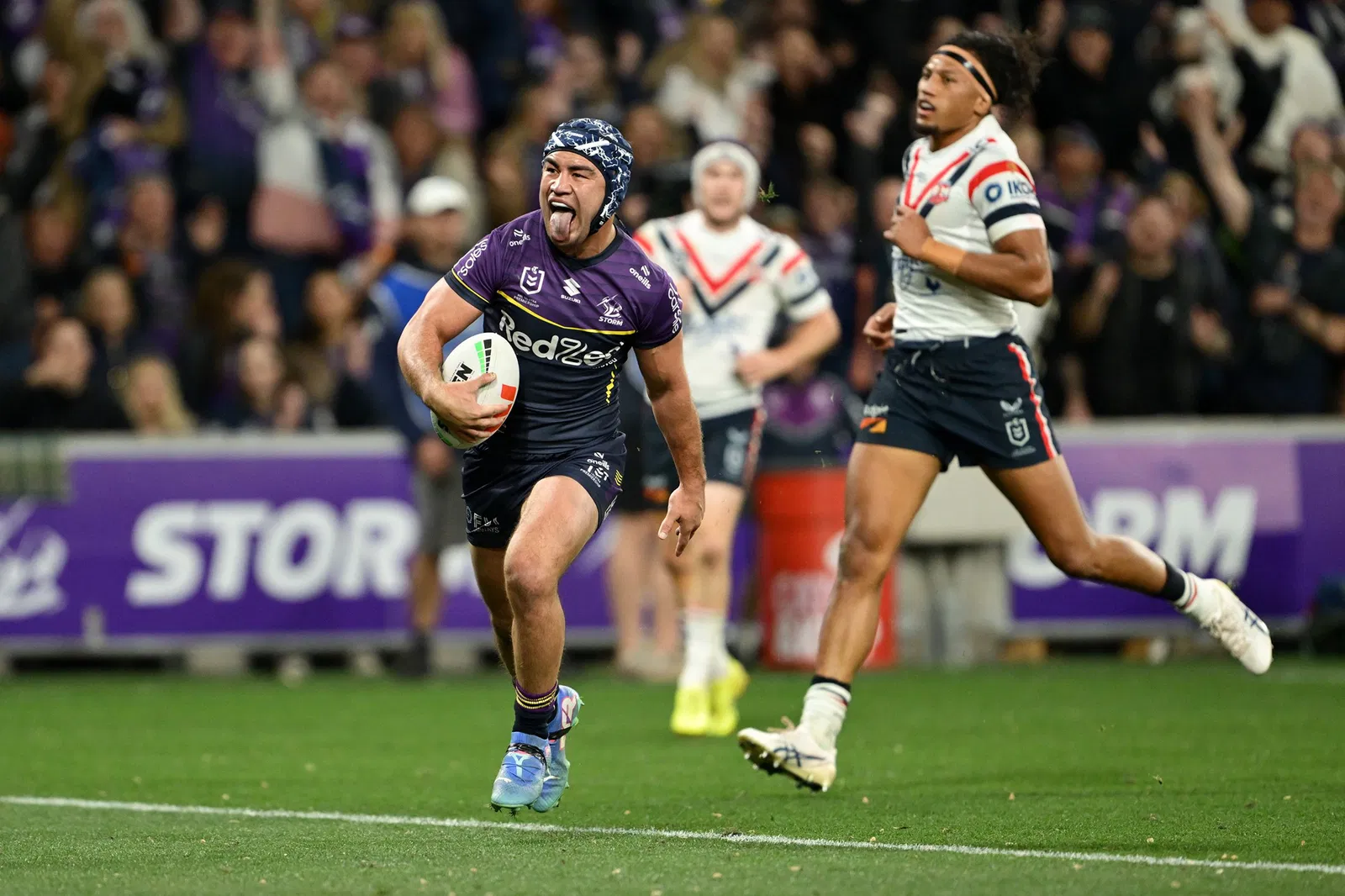 Jahrome Hughes sticks his tongue out as he runs in for a Melbourne Storm try.