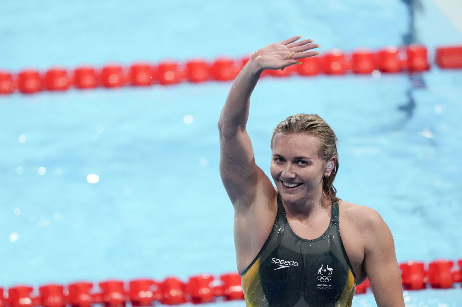 Ariarne Titmus smiles and waves to the crowd poolside
