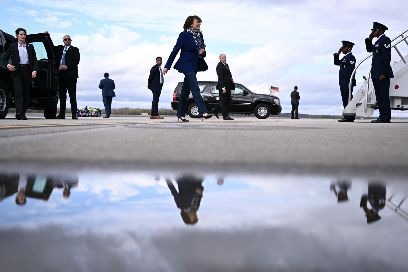 Harris walks across a tarmac toward the steps of Air Force Two, as men in suits stagger behind her