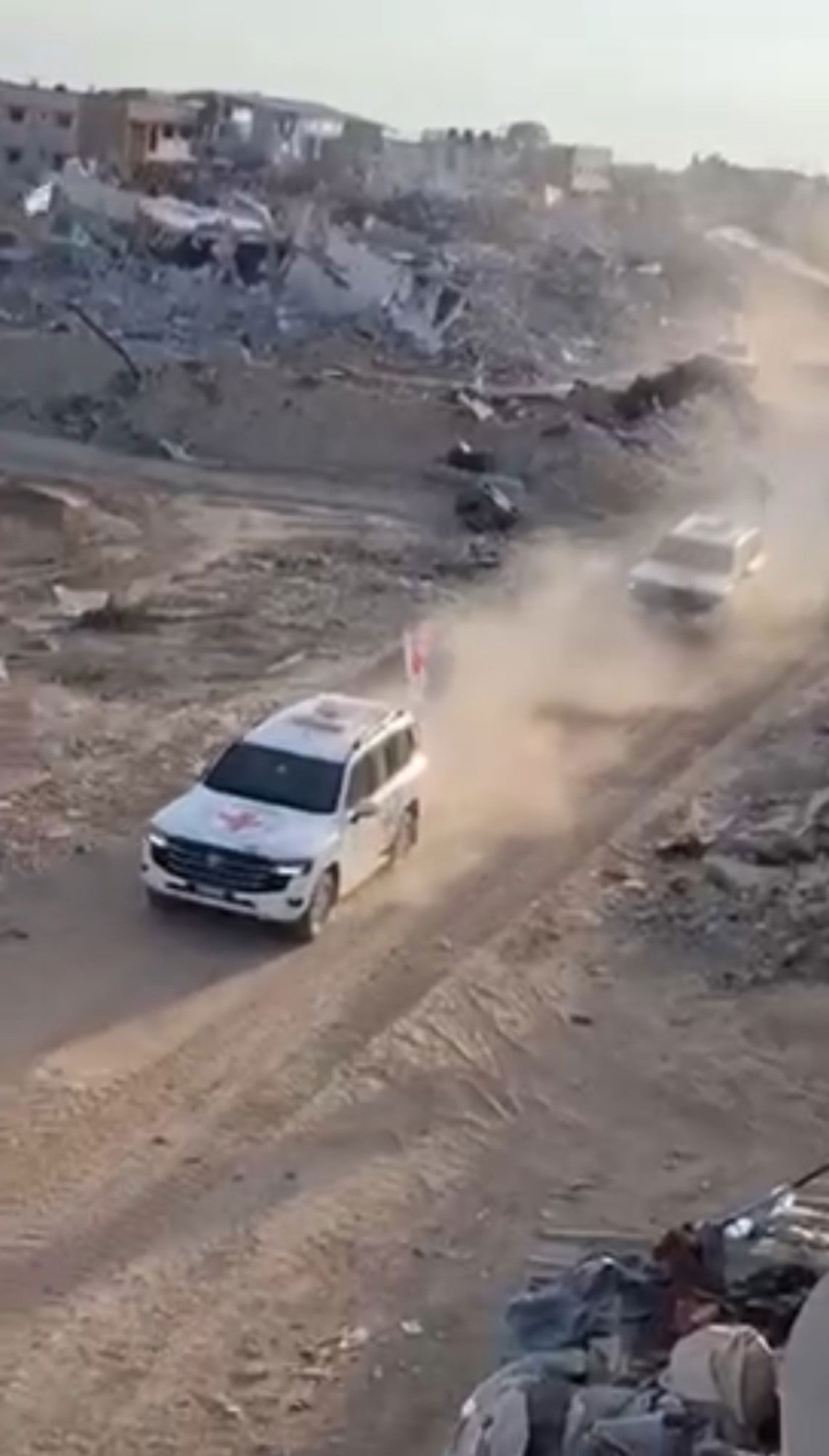 Several cars driving on a dirt road.