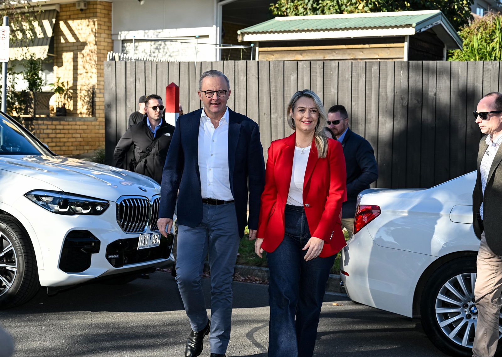 Anthony Albanese wearing a black jacket and dark pants walking alongside Jodie Haydon in a red blazer