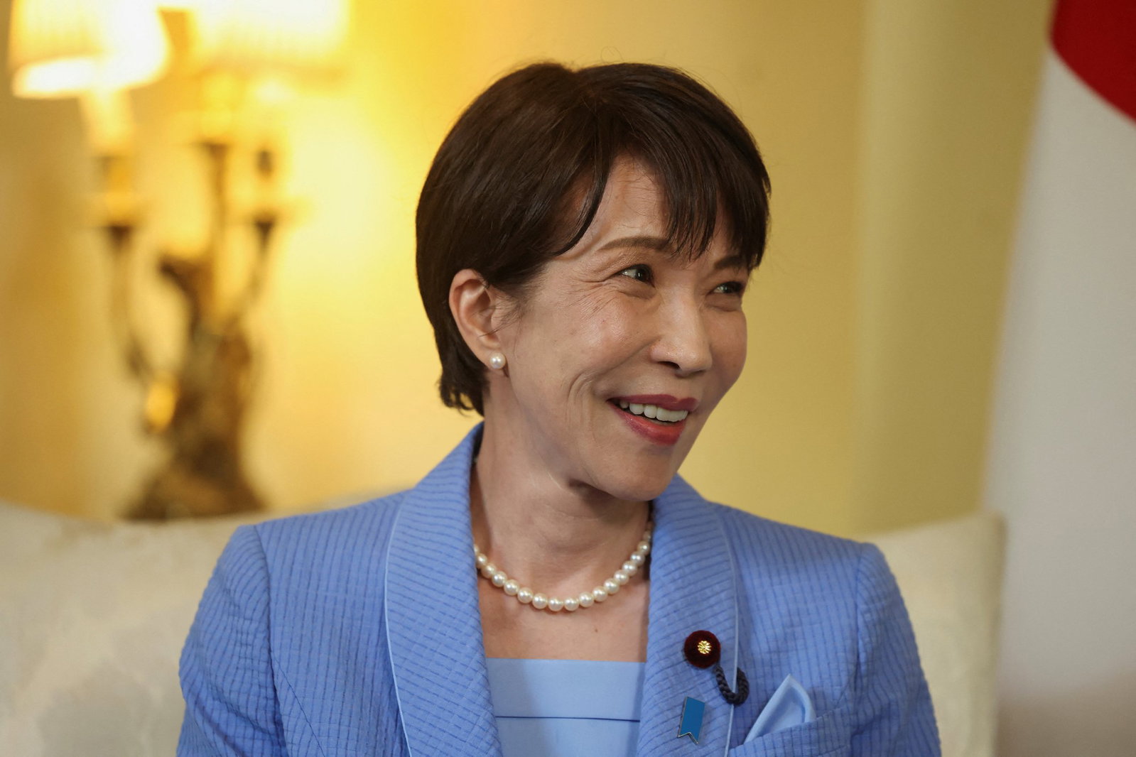 A Japanese woman with short hair smiles looking to the side.