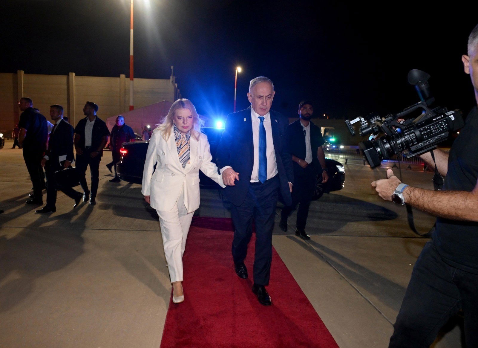 A man and a woman, both wearing suits, walk.