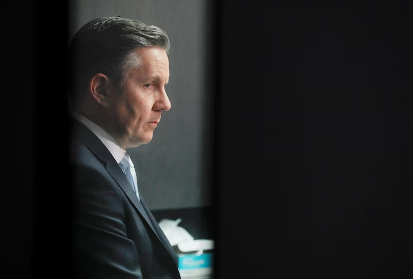 Man in suit stands in the sidelines