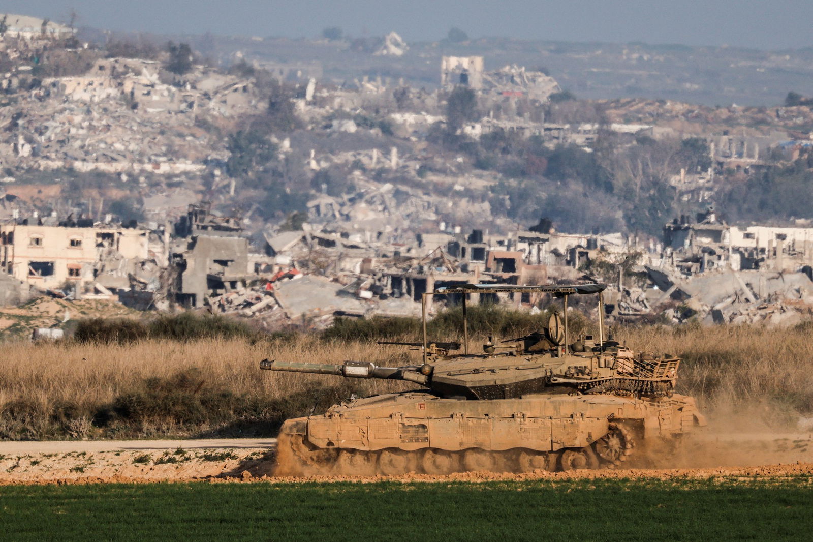 An army tank in front of building debris. 