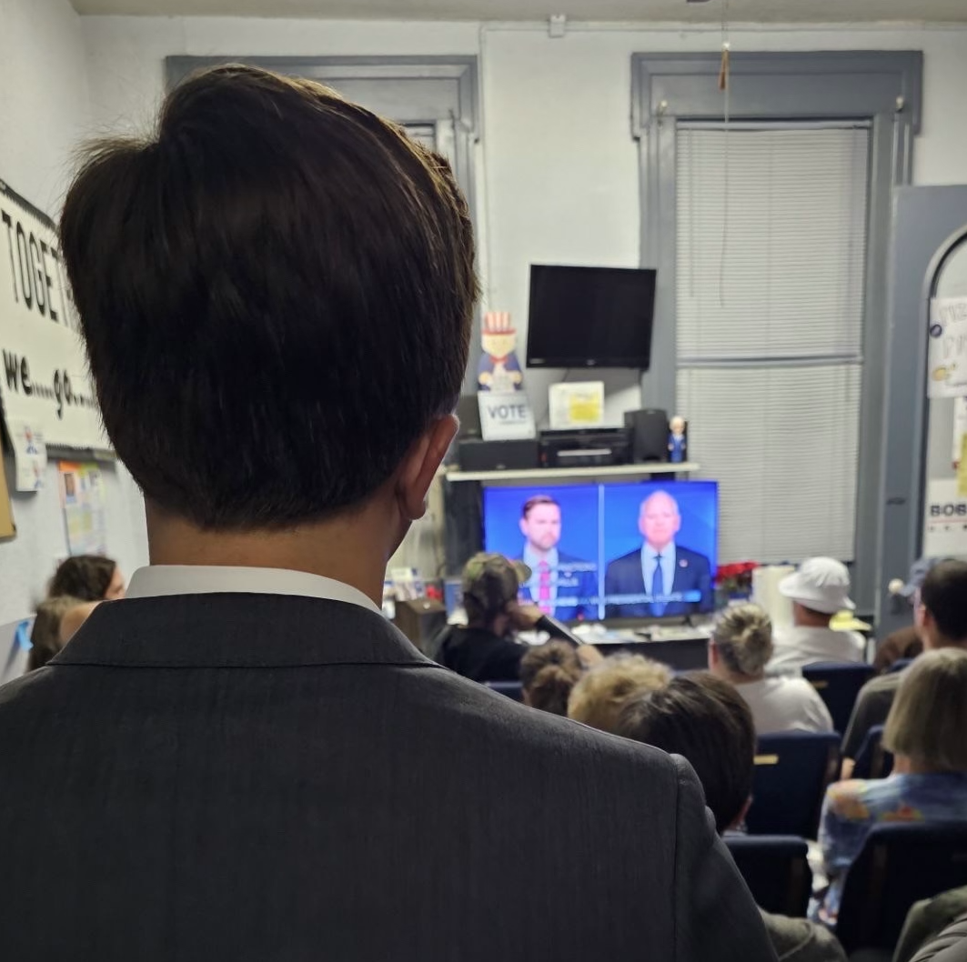 A man watches the debate in a room of people.