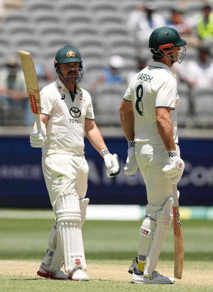 Travis Head raises his bat after reaching 50.