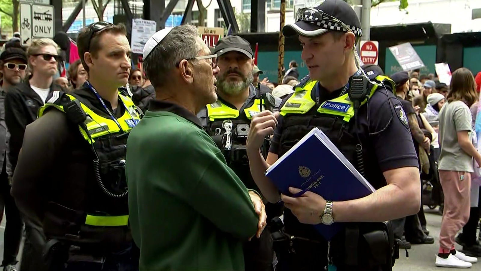 A man being told to move away from a protest by police.