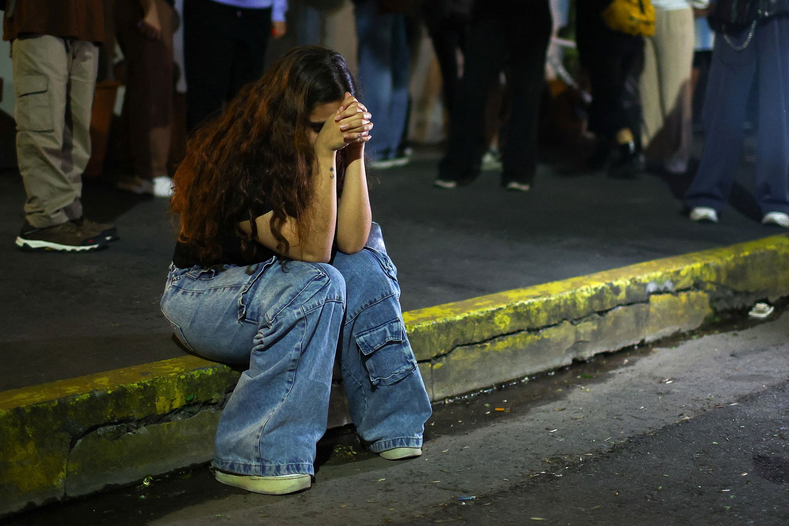 A woman sits on the curb 