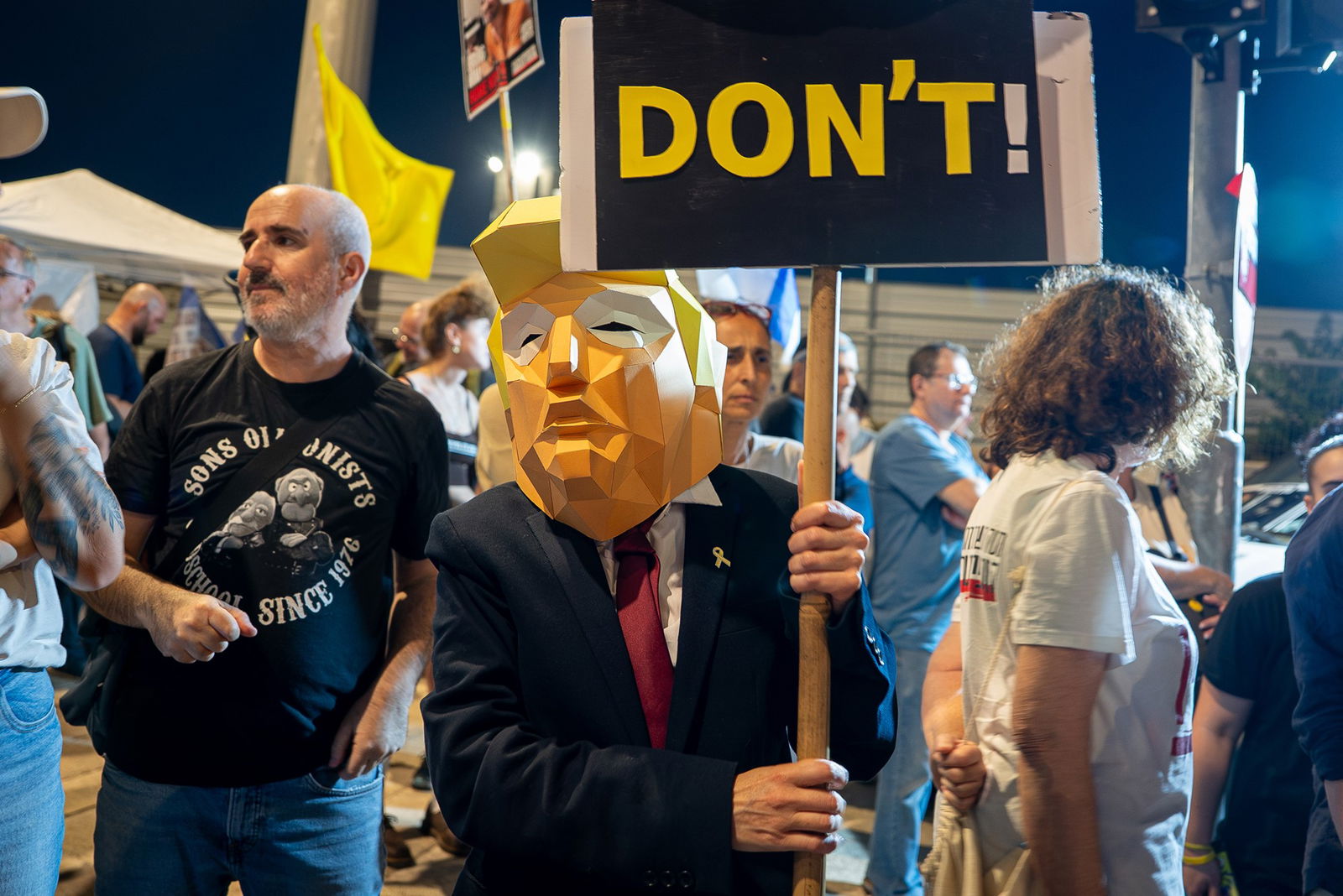 A person a suit and Trump head holds a sign saying 'Don't'.