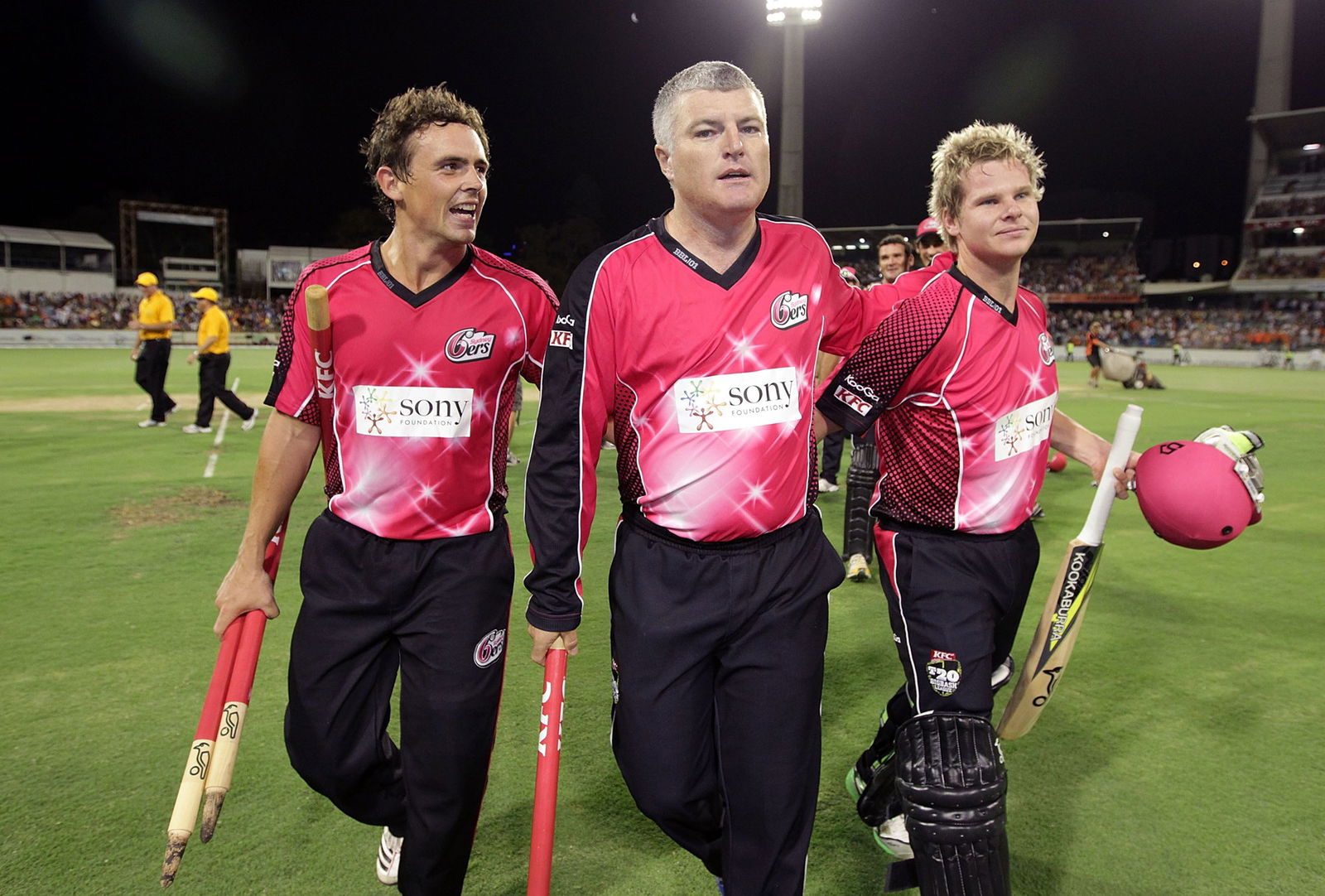 Tres jugadores de críquet vestidos de rosa abandonan el campo