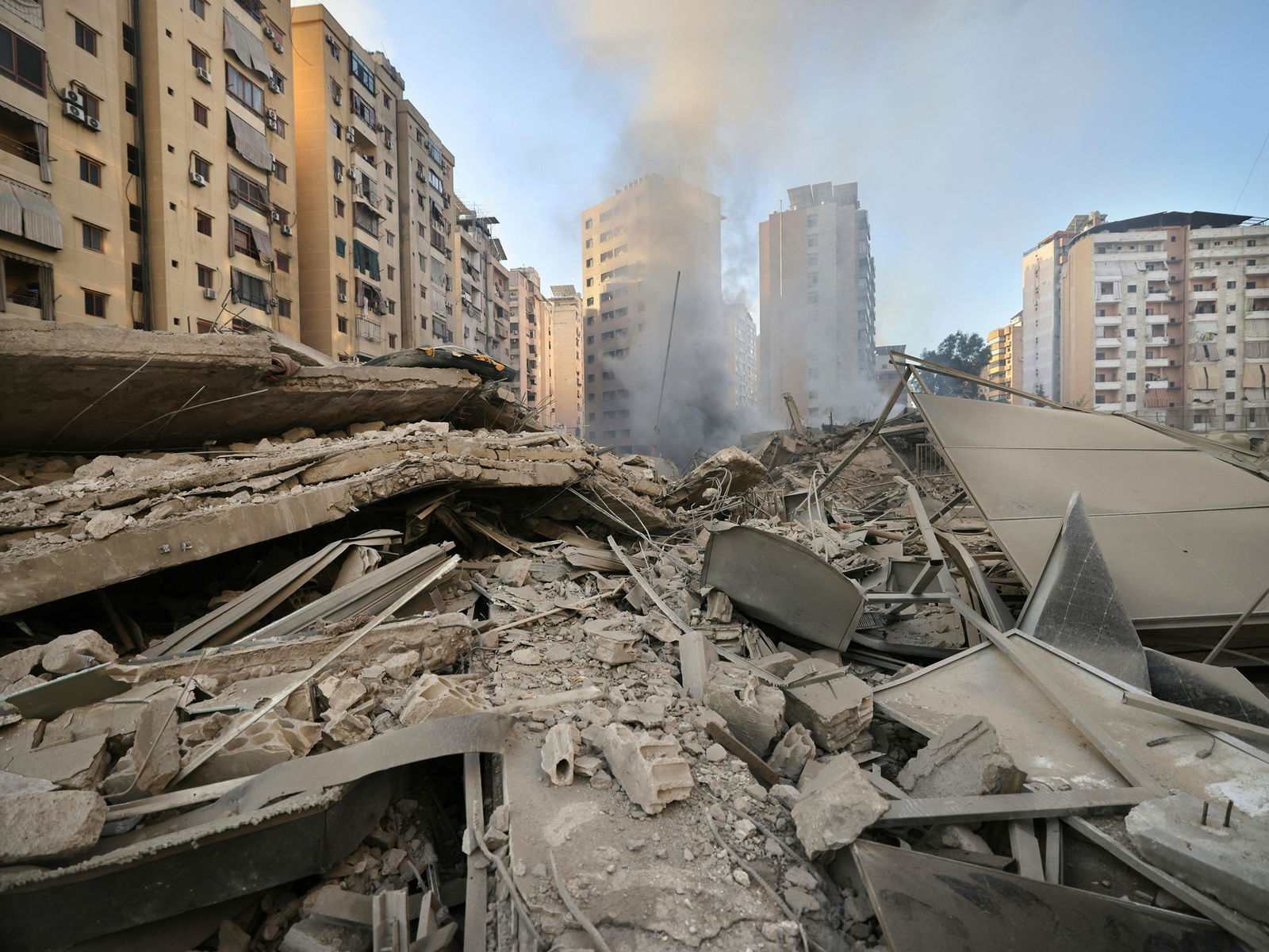 Rubble in the foreground; smoke and buildings in the background