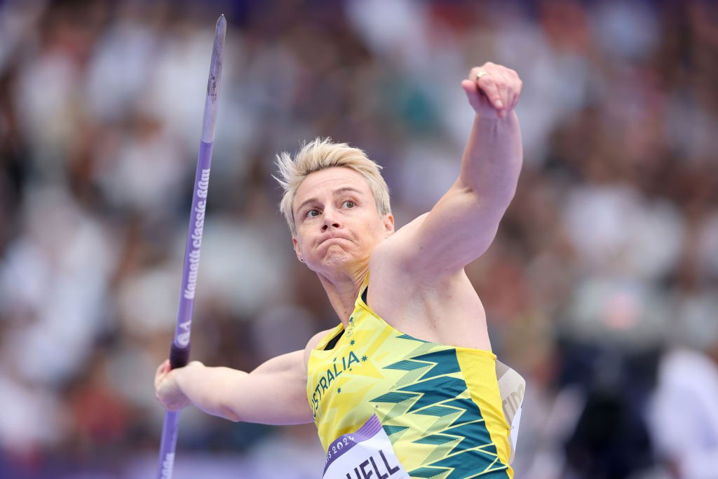 A woman with short blonde hair throws a javelin.