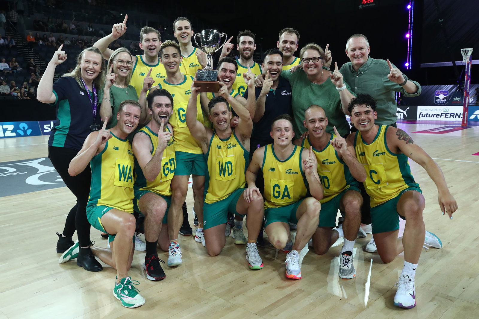 A group of male netballers pose together with a trophy