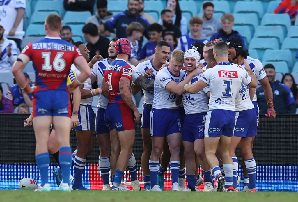 Bulldogs players hug each other after a try against the Knights.