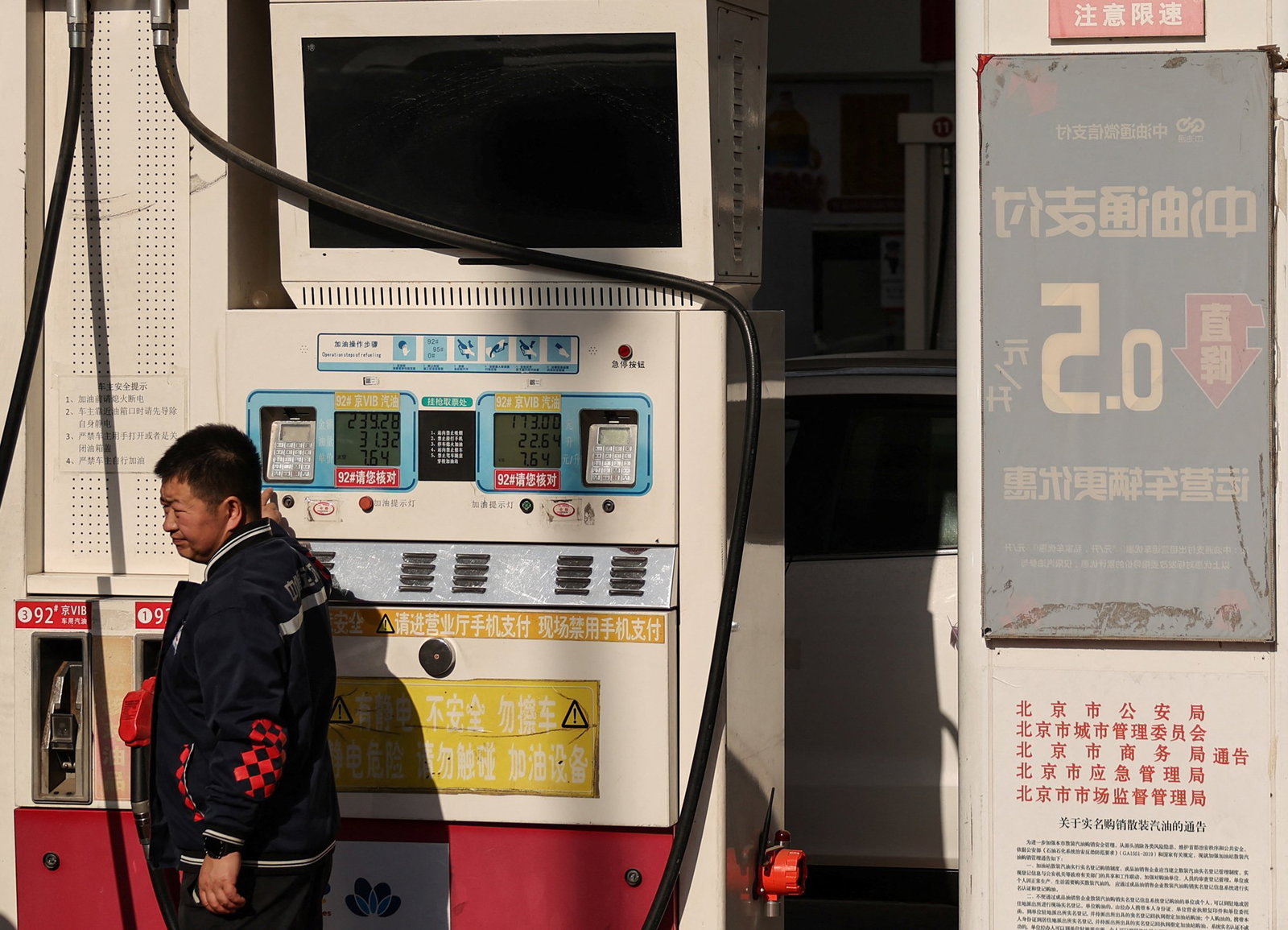 A man stands next to a petrol pump in China.