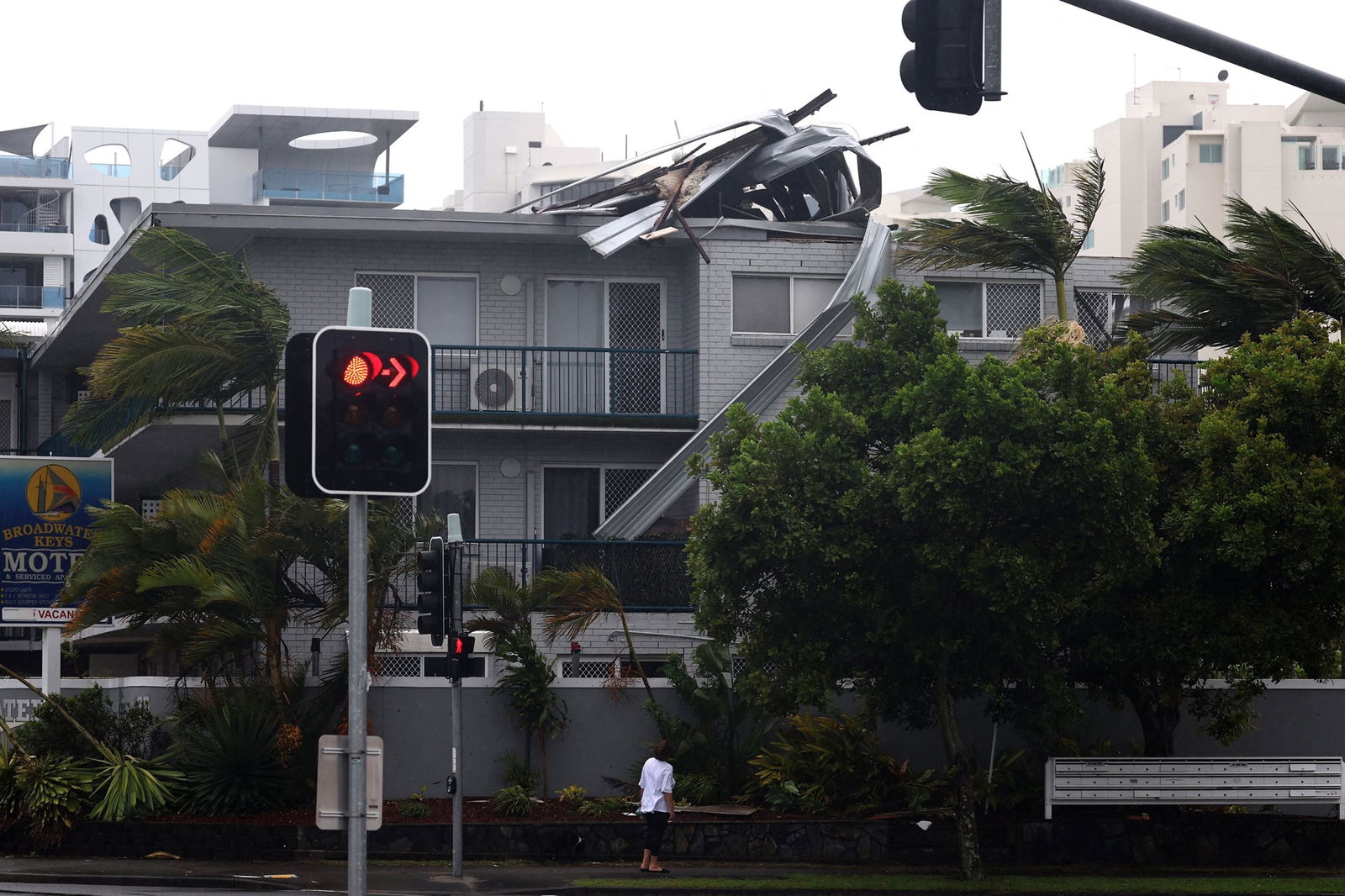 A woman surveys the damage to the roof of a motel caused by strong winds in Labrador, near the Gold Coast.