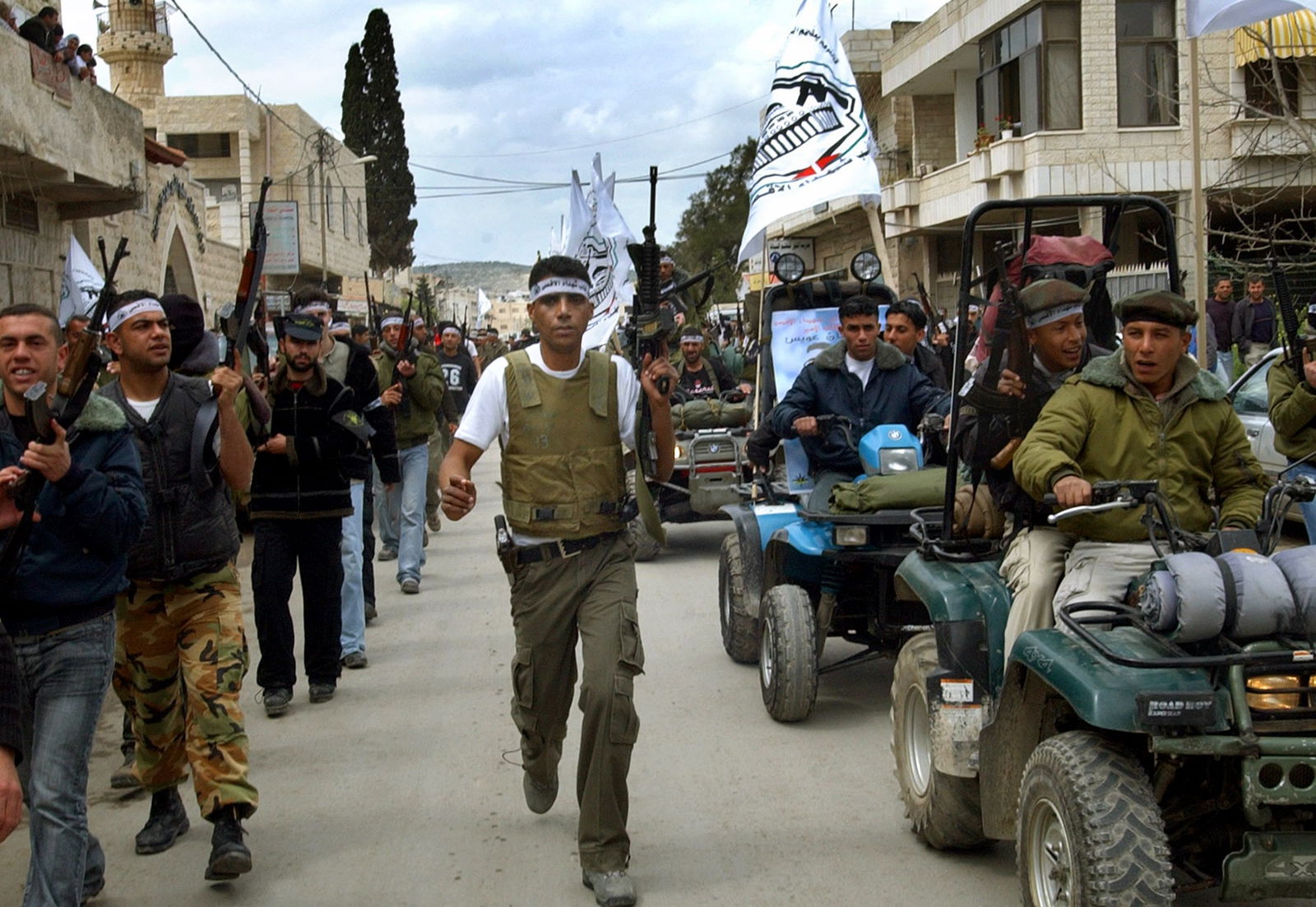 A large number of people with guns, walking, with one man clearly visible in the centre.