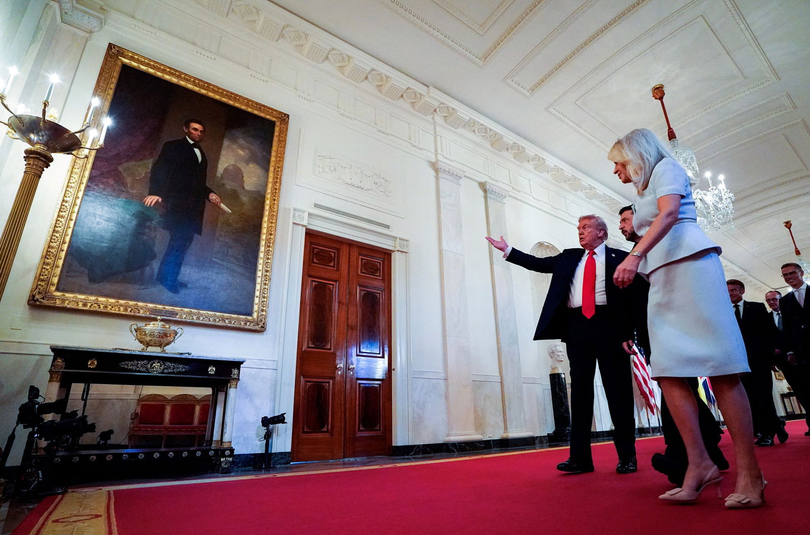 Trump gestures to a large portrait of Abraham Lincoln in a White House hall